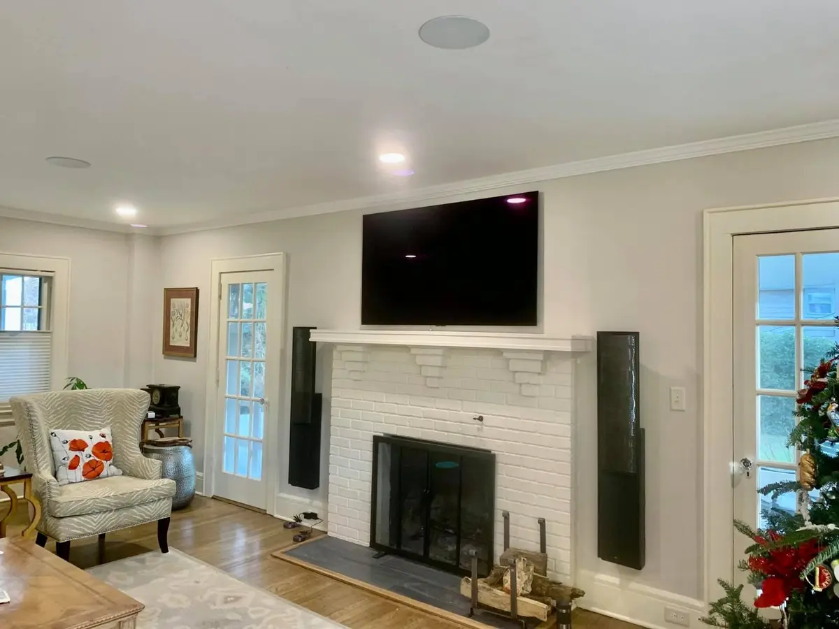 Television mounted above brick fireplace with in-ceiling speakers